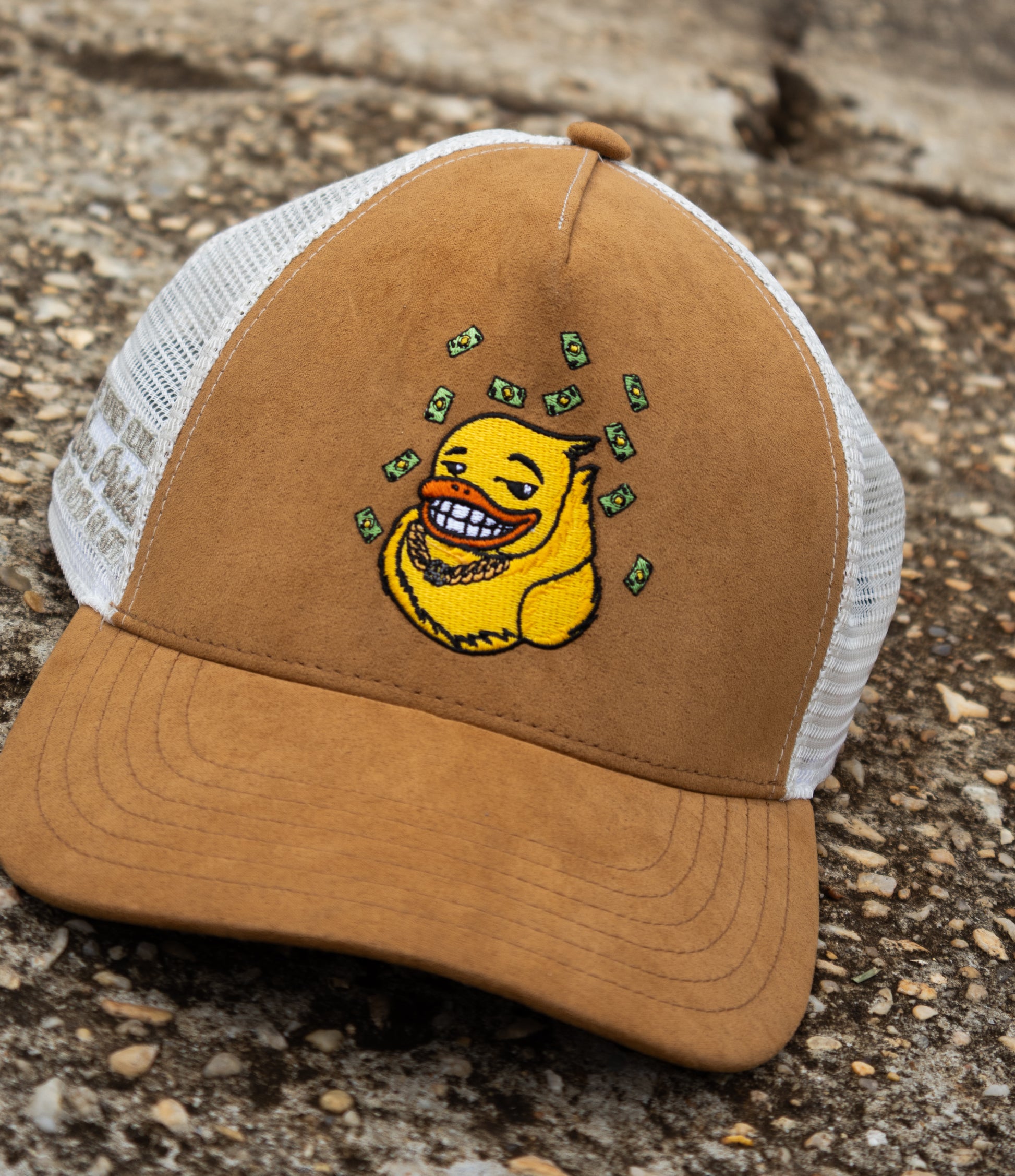 Brown and white cap with an embroidered yellow duck graphic on a textured surface